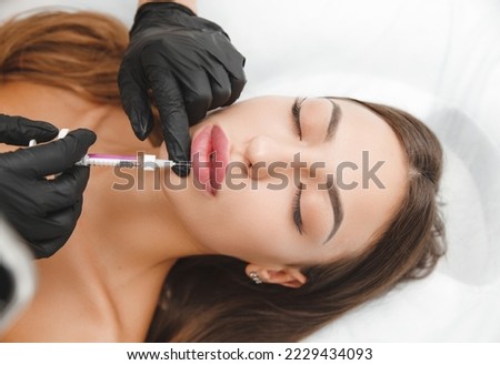 female lips, lip augmentation procedure. A syringe near a woman's mouth, injections to increase the shape of the lips Royalty-Free Stock Photo #2229434093
