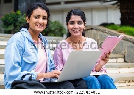 focus on girl with book, Happy College students looking at camera while busy working on laptop on university campus - concept of education, teamwork and friendship