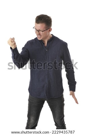 Handsome angry man in a dark blue shirt and jeans crumpling paper sheet isolated on white background