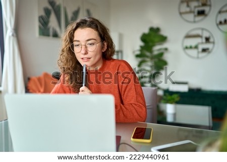Young girl female student using laptop elearning or remote working at home office looking at computer watching webinar, learning training, studying online seminar or video calling for work meeting. Royalty-Free Stock Photo #2229440961