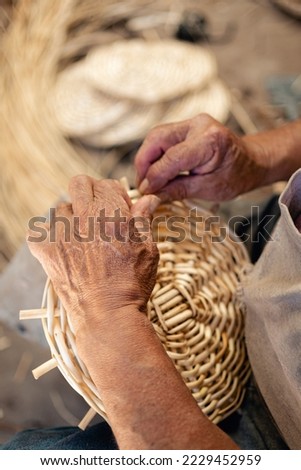 Close up caption of man hands weaving wicker for a craft basket. Vertical photography. South American culture and Tradition Royalty-Free Stock Photo #2229452959