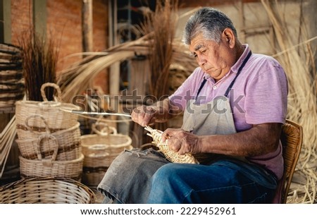 South American old man weaving wicker basket at his workshop. Culture and Tradition concept Royalty-Free Stock Photo #2229452961