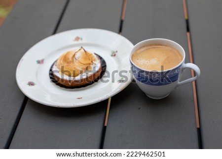 a cup of black coffee with foam, rainy day, sweet tart on a plate
