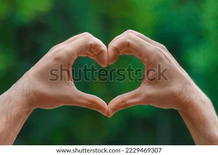 Man making heart with hands outdoors, closeup