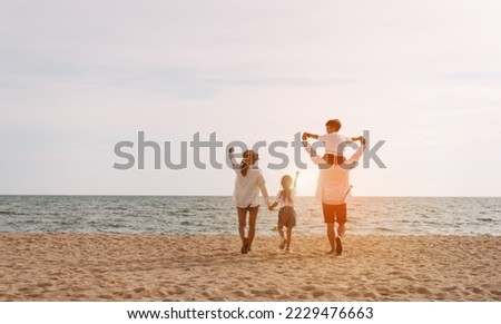 Happy asian family on the beach in holiday. of the family holding hands, Son and daughter piggyback on parents.They are having fun playing enjoying the sunset on the beach. Summer Family and lifestyle