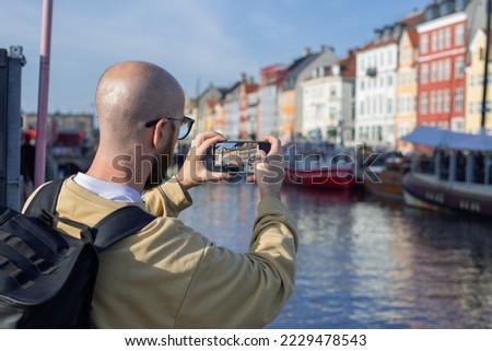 tourist takes picture historic sailing ship moored at the pier in the center of copenhagen with his phone 