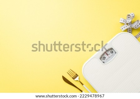 Weight loss concept. Top view photo of cutlery knife fork tape measure and scales on isolated pastel yellow background with copyspace