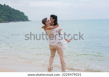 Romatic couple passionately kissing on dock. Happy groom holding excited bride in his arms. Groom carrying his bride at the beach