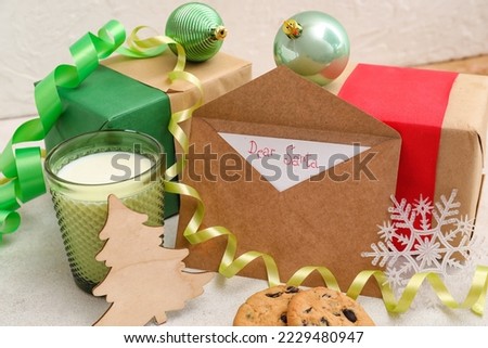 Letter to Santa with glass of milk, cookies, presents and Christmas decor on white background