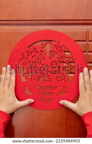 man sticking a Chinese New Year of Rabbit paper cut decoration to a door at vertical composition