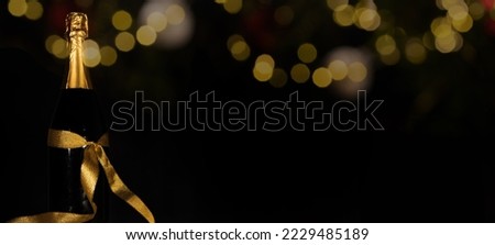 HAPPY NEW YEAR 2023 festive celebration holiday New Year's Eve greeting card background - Champagne or sparkling wine bottles with golden gift ribbon and bokeh lights on dark night sky