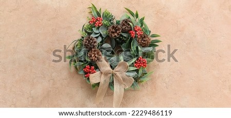 Beautiful Christmas wreath decorated with cones and rowan berries on beige background