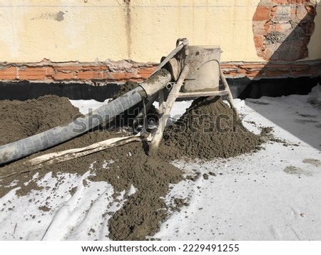 Portland cement mortar machine pouring mortar in a walkable roof. Photo of a construction site using mortar for the deck's floor. Working with dry cement, sand and mortar and pumping it with a tube.