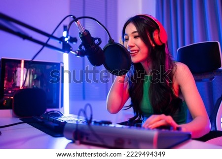 Asian beautiful Esport woman gamer play online video game on computer. Attractive young girl gaming player feel happy and enjoy technology broadcast live streaming while plays cyber tournament at home Royalty-Free Stock Photo #2229494349