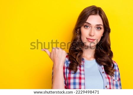 Photo of adorable pretty young lady wear plaid shirt pointing finger empty space isolated yellow color background