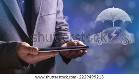 Electric car and umbrella from the net. Man holding a tablet in his hand
