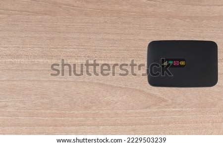 Portable pocket wifi modem on wooden background. Black wifi  portable pocket modem top view.  Royalty-Free Stock Photo #2229503239