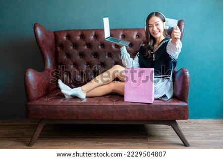 Young woman on sofa shopping online with laptop, Young woman holding credit card and using laptop computer. Online shopping concept	