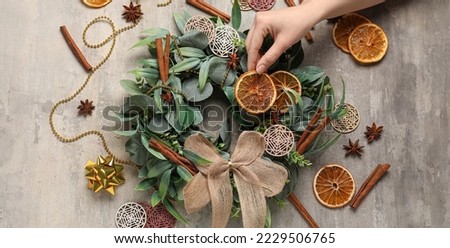 Woman making beautiful Christmas wreath on grunge background, top view