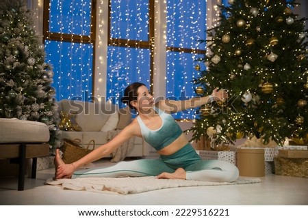 and doing yoga fitness exercise  in the Christmas interior  at home. home fitness, activewear. Healthy and sport lifestyle. Christmas holidays