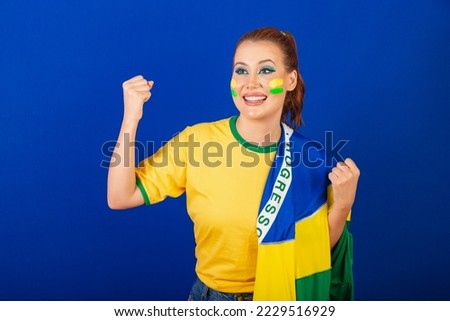 Caucasian woman, redhead, Brazil soccer fan, Brazilian, blue background, wearing flag of Brazil, celebrating