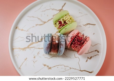 Colorful large macaroons on a beautiful plate, with various fillings. On a pink background. Photo for content.