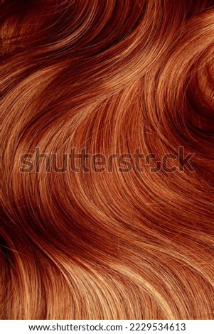 Red hair close-up as a background. Women's long orange hair. Beautifully styled wavy shiny curls. Hair coloring bright shades. Hairdressing procedures, extension. Royalty-Free Stock Photo #2229534613