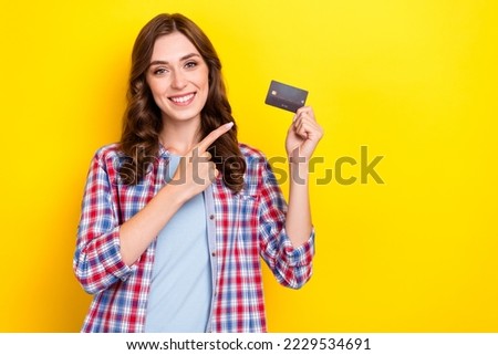 Photo of shiny pretty lady wear plaid shirt pointing finger plastic card empty space isolated yellow color background