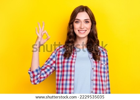 Photo of cheerful positive young lady wear plaid shirt showing okey sign isolated yellow color background