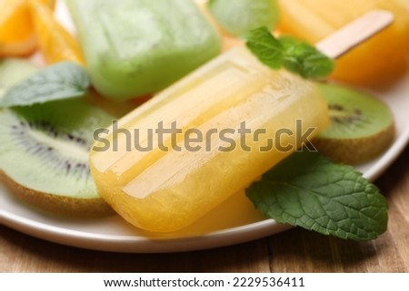 Plate of tasty orange and kiwi ice pops on table, closeup. Fruit popsicle