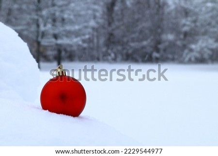 Winter decorations in the snow. Red Christmas ball. Minimalistic photo. Stockholm, Sweden.