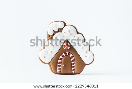 Christmas gingerbread house shaped cookie with white snow icing isolated on white background. Homemade festive traditional cookies. Merry Christmas greeting