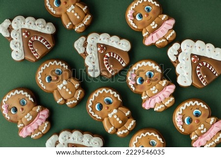 Christmas gingerbread house shaped cookies with white snow icing on a green background. Homemade festive traditional gingerbread man. Merry Christmas greeting. Flat lay