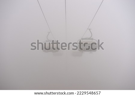 Amusement park rides, excursion with ski lift in the fog. Natural park background, abstract scenic landscape in mountains. Vacation trip ideas Royalty-Free Stock Photo #2229548657