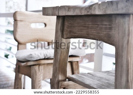 Terrace of a wooden house overlooking the winter forest. On the terrace there is a wooden chair with a soft cushion for the seat. Horizontal photo