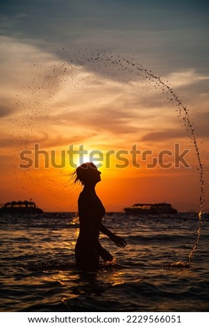 woman silhouette in the sea at sunset