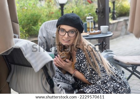 A young, beautiful girl with a kitten and bread on the streets of the city.