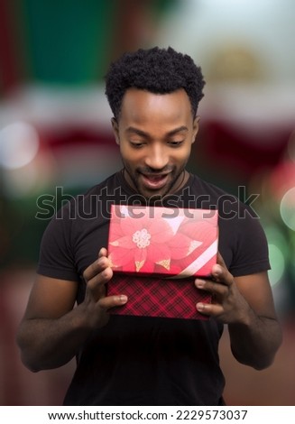 young man receiving a gift and opening box christmas night surprise holiday surprise decorated window