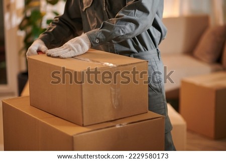 Movers packing boxes and securing with adhesive tape Royalty-Free Stock Photo #2229580173