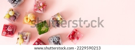 Frozen ice cubes with various fruits banner, blackberries and raspberries, gooseberries and currants, blueberries and mint, top view