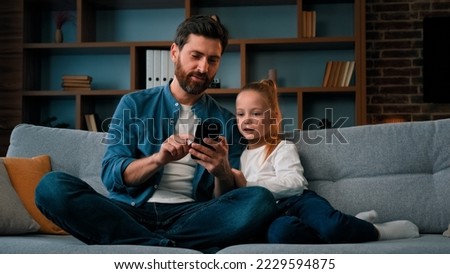 Happy family young child girl and single daddy look at modern gadget smartphone watch video online together internet communication caucasian father teach daughter kid use mobile phone parental control