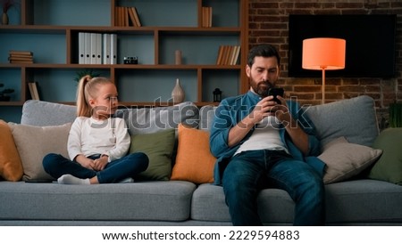 Bored child girl resting at home with father young dad using mobile phone little kid need attention looking at daddy taking modern gadget young family generation internet technology addiction concept Royalty-Free Stock Photo #2229594883