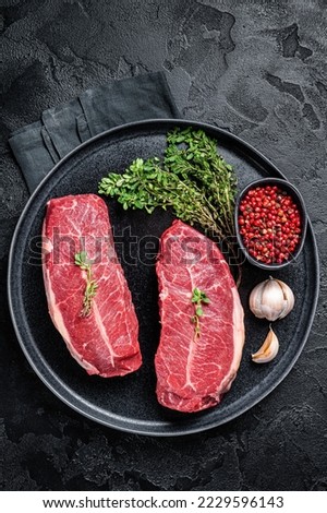 Dry aged Raw top blade flat Iron beef meat steaks. Black background. Top View. Royalty-Free Stock Photo #2229596143