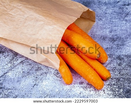 Fresh raw carrots in paper bag on the table