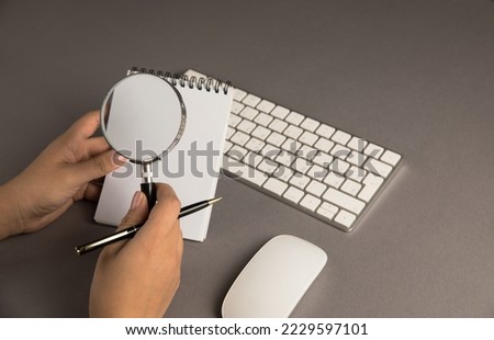 Woman looking at paper with a magnifying glass in front of her desk