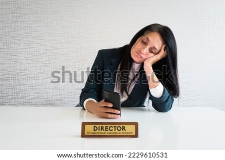 Young caucasian brunette business woman director in office sit at desk use phone scroll news social media bored at work director funny. Unnecessary employee office prank plate
