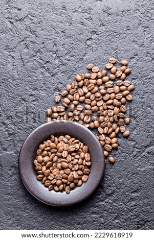 Roasted coffee beans on a plate, on a dark background, close-up image, space for text