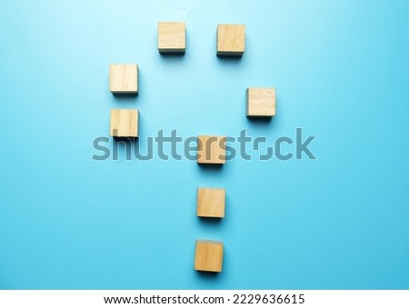 A picture of wooden block been arranged in question mark shape on blue background.