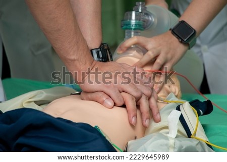 Demonstrating CPR (Cardiopulmonary resuscitation) training medical procedure on CPR doll in the class.Paramedic demonstrate first aid practice for save life.Doctor holding breathing bag(Ambu bag). Royalty-Free Stock Photo #2229645989