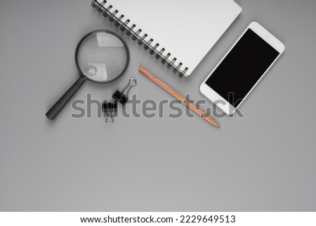 Top view accessories office concept. Mobile phone, notepaper, pen, Magnifying glass on office desk.